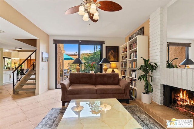 tiled living room featuring a brick fireplace and ceiling fan