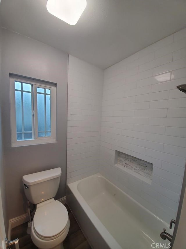 bathroom with wood-type flooring, tiled shower / bath combo, and toilet