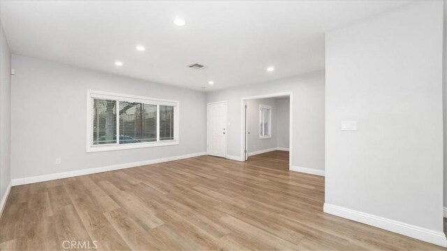 empty room featuring light wood-type flooring, visible vents, baseboards, and recessed lighting