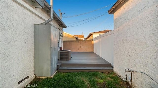 view of side of home with central AC, fence, and stucco siding