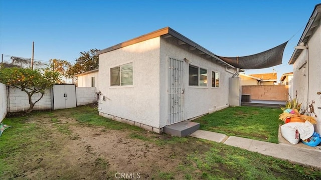 view of side of property with a yard, a fenced backyard, and stucco siding