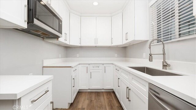 kitchen with stainless steel appliances, light countertops, a sink, and white cabinetry