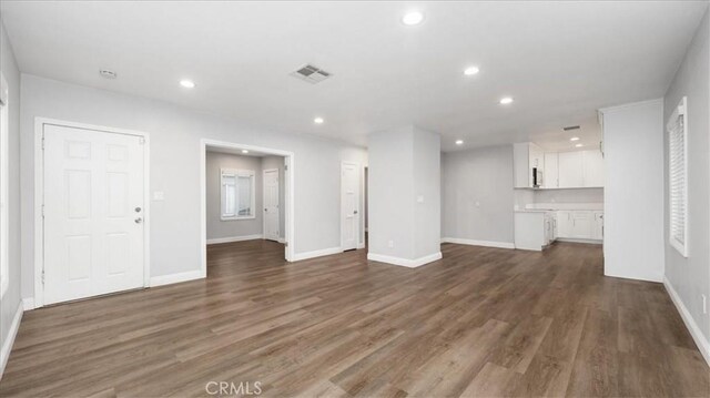 unfurnished living room with dark wood-style floors, baseboards, visible vents, and recessed lighting