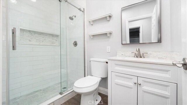 full bath with toilet, wood finished floors, a shower stall, and vanity