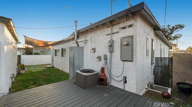 exterior space featuring central AC, fence, a wooden deck, and stucco siding