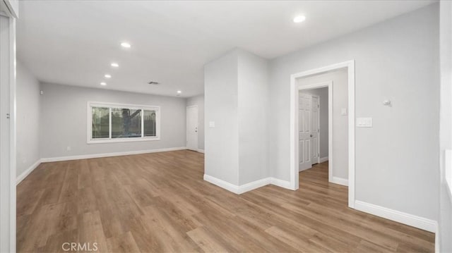 empty room featuring recessed lighting, baseboards, and light wood finished floors