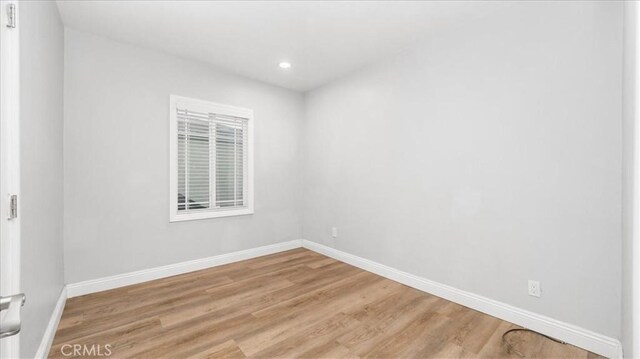 empty room with light wood finished floors, recessed lighting, and baseboards