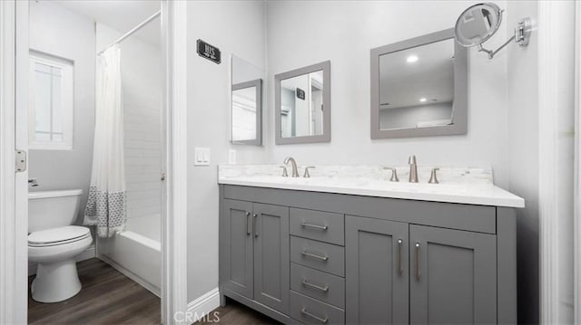 full bath with toilet, shower / bathtub combination with curtain, a sink, and wood finished floors