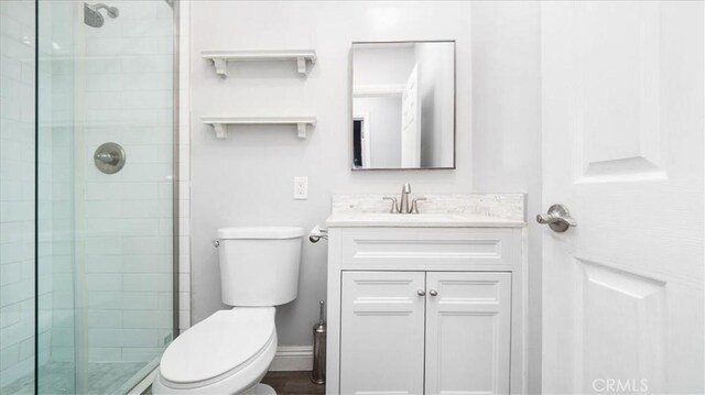 full bathroom with a stall shower, baseboards, vanity, and toilet