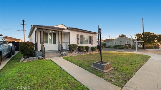 bungalow with a front yard and stucco siding