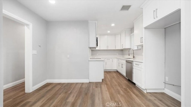 kitchen with baseboards, wood finished floors, light countertops, white cabinetry, and stainless steel dishwasher