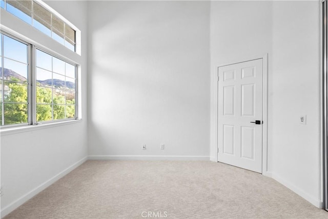 carpeted empty room with a mountain view and a high ceiling