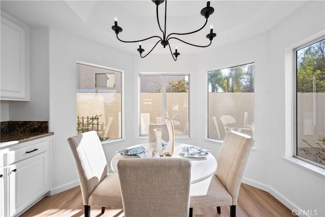 dining room with light wood-type flooring, a wealth of natural light, and an inviting chandelier