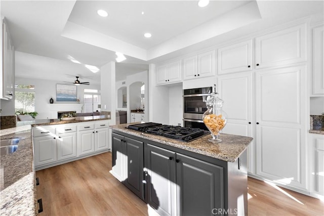 kitchen with a raised ceiling, black gas stovetop, white cabinetry, and double oven