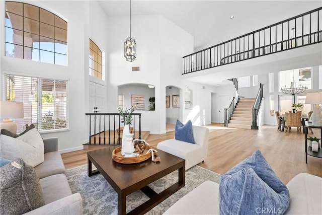 living room with light hardwood / wood-style floors, a high ceiling, and a chandelier