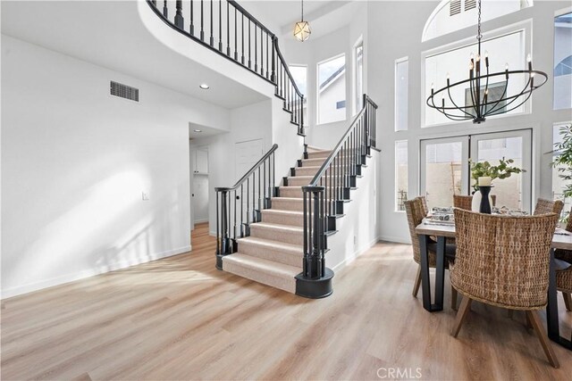 dining space with a towering ceiling, light hardwood / wood-style floors, and an inviting chandelier