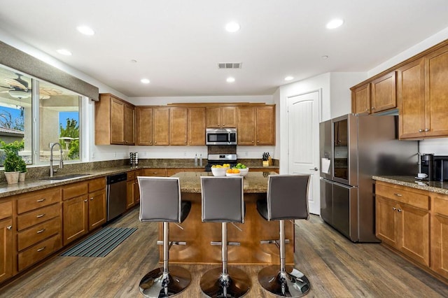 kitchen with sink, a center island, dark wood-type flooring, and appliances with stainless steel finishes