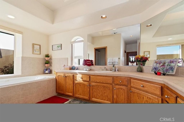 bathroom featuring vanity and tiled bath