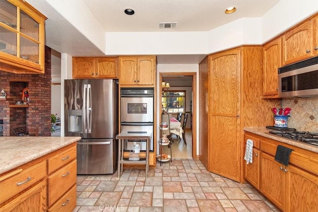 19985 Red Feather Rd, Apple Valley, CA 92307 - kitchen with stainless steel appliances, light countertops, light stone finish flooring, glass insert cabinets, and decorative backsplash