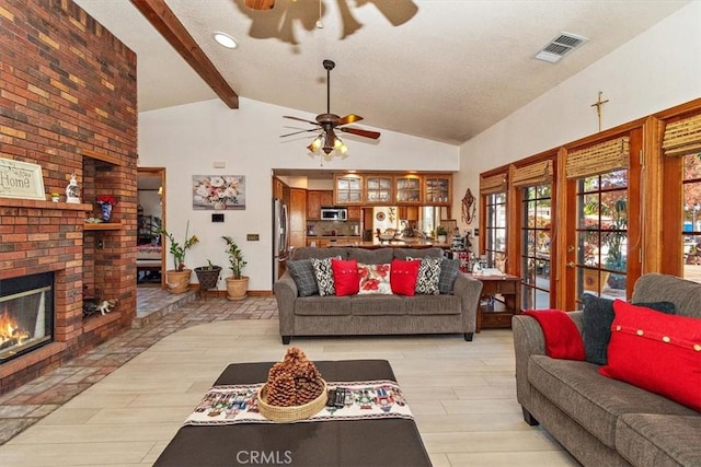 living room featuring ceiling fan, light hardwood / wood-style flooring, lofted ceiling with beams, and a brick fireplace