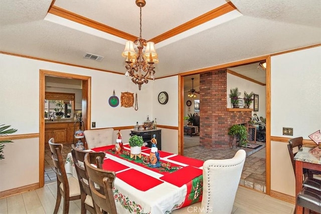 19985 Red Feather Rd, Apple Valley, CA 92307 - dining room with a tray ceiling, a chandelier, light wood finished floors, crown molding, and a textured ceiling