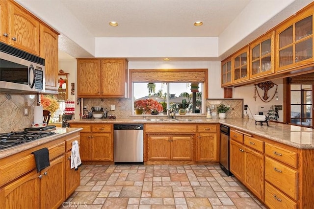 19985 Red Feather Rd, Apple Valley, CA 92307 - kitchen with stainless steel appliances, tasteful backsplash, glass insert cabinets, a peninsula, and light stone finish floors