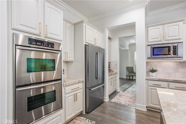 kitchen featuring light stone countertops, appliances with stainless steel finishes, tasteful backsplash, dark wood-type flooring, and white cabinetry