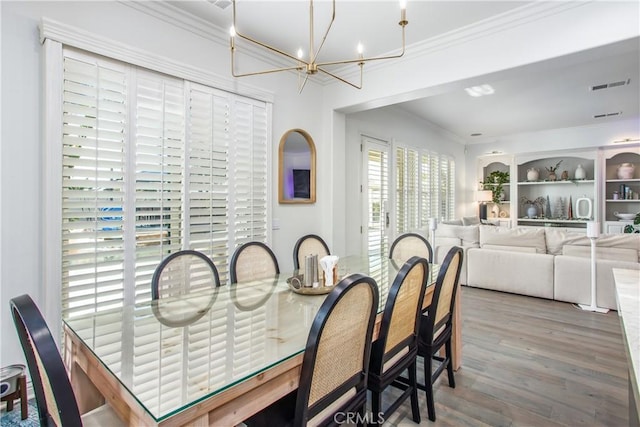 dining space with hardwood / wood-style flooring, crown molding, and a chandelier