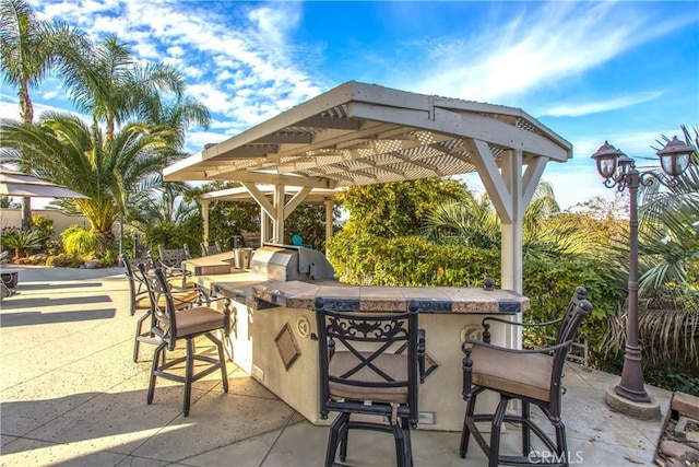 view of patio with exterior bar, a pergola, and area for grilling