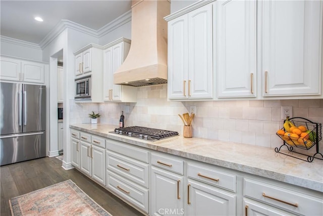 kitchen with tasteful backsplash, premium range hood, stainless steel appliances, dark wood-type flooring, and white cabinets