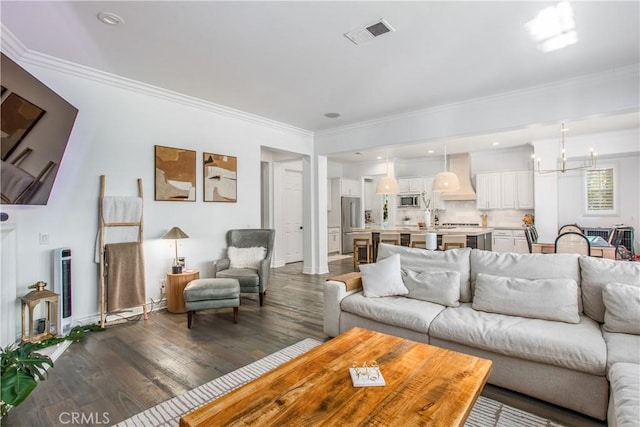 living room featuring a chandelier, dark hardwood / wood-style flooring, and ornamental molding