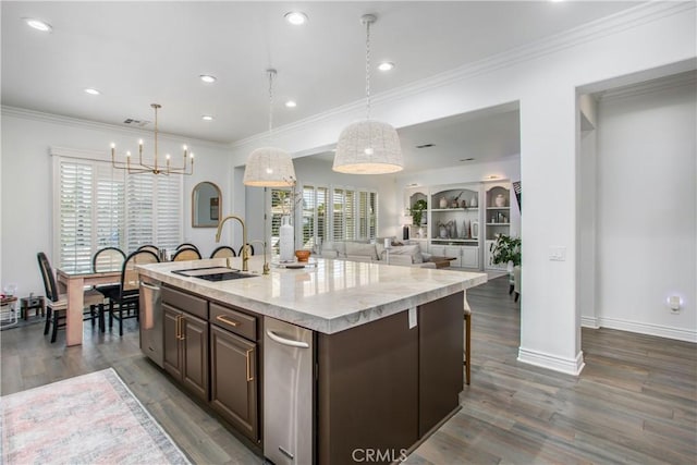 kitchen with dark hardwood / wood-style floors, dark brown cabinets, an island with sink, and decorative light fixtures