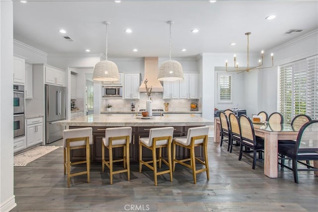 kitchen with premium range hood, white cabinets, appliances with stainless steel finishes, a large island, and dark hardwood / wood-style flooring