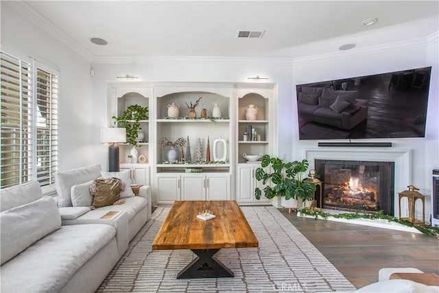 living room with hardwood / wood-style flooring, built in features, and ornamental molding