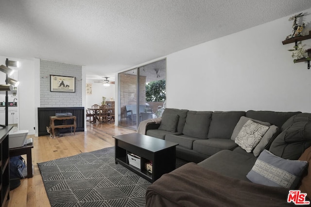 living room with a textured ceiling, hardwood / wood-style flooring, and ceiling fan