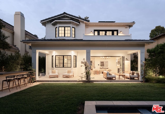 rear view of house featuring a lawn, a patio area, a balcony, and an outdoor bar