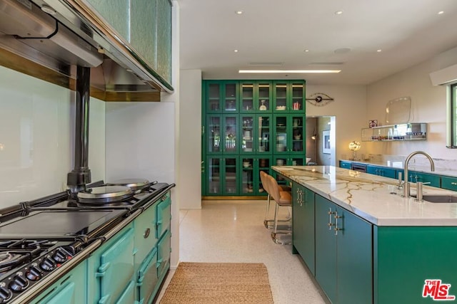 kitchen featuring stainless steel gas stovetop, sink, an island with sink, and green cabinetry