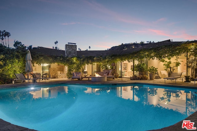 pool at dusk featuring a patio area