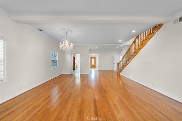 unfurnished living room featuring a wealth of natural light, ornamental molding, stairs, and light wood finished floors