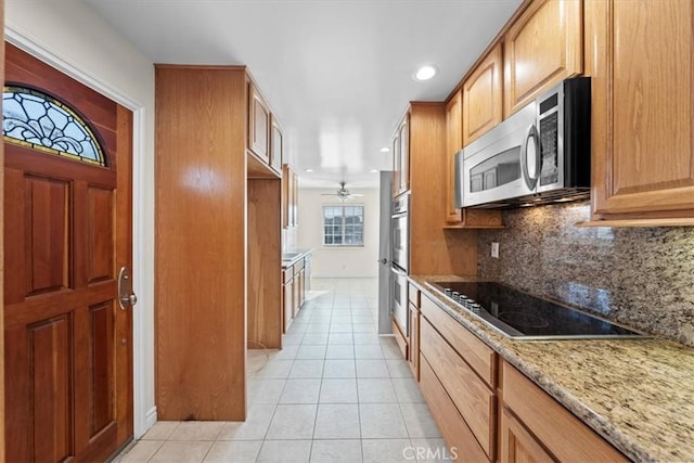 kitchen with light stone counters, backsplash, recessed lighting, appliances with stainless steel finishes, and light tile patterned floors