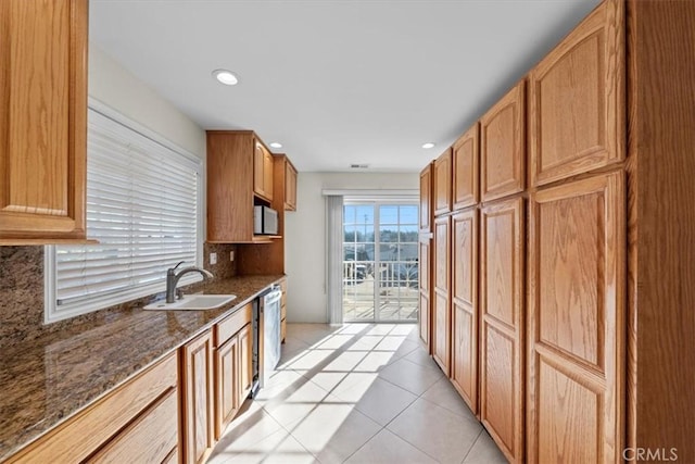 kitchen featuring a sink, decorative backsplash, dark stone countertops, light tile patterned flooring, and stainless steel dishwasher