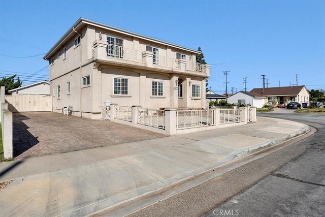 view of front of property with a balcony, a gate, a fenced front yard, and stucco siding