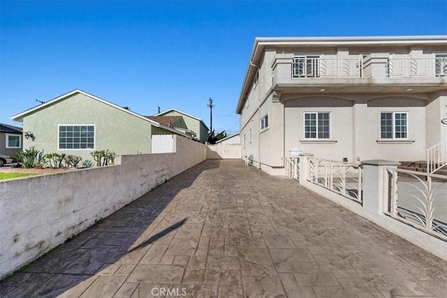 exterior space featuring a balcony, fence, and stucco siding