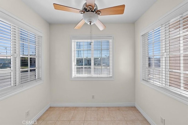 spare room featuring light tile patterned floors, baseboards, and ceiling fan