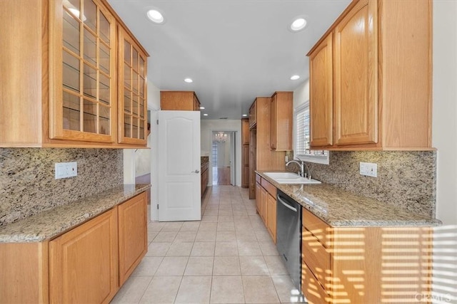 kitchen with light stone counters, glass insert cabinets, and a sink