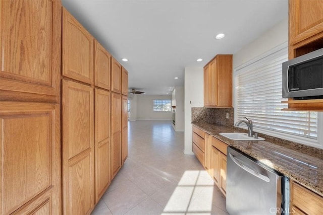 kitchen with a sink, recessed lighting, stainless steel appliances, dark stone counters, and decorative backsplash