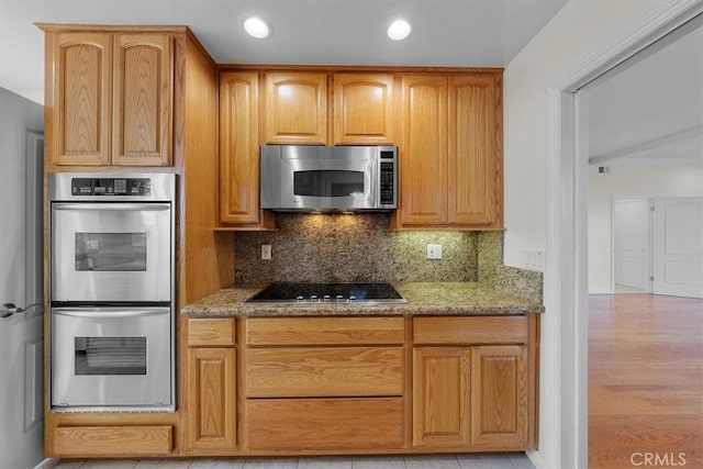 kitchen with light stone counters, recessed lighting, tasteful backsplash, and appliances with stainless steel finishes