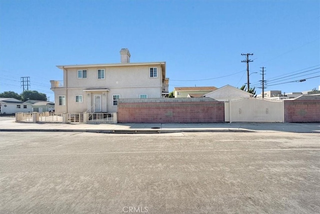 back of property with a gate, a fenced front yard, and stucco siding