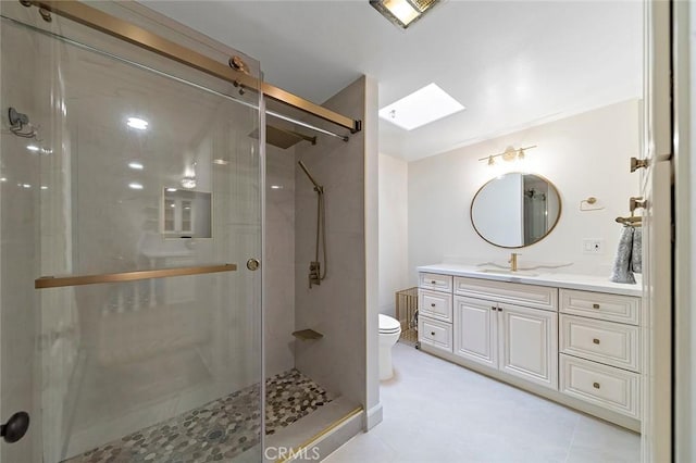 bathroom featuring a skylight, tile patterned floors, vanity, a shower with door, and toilet