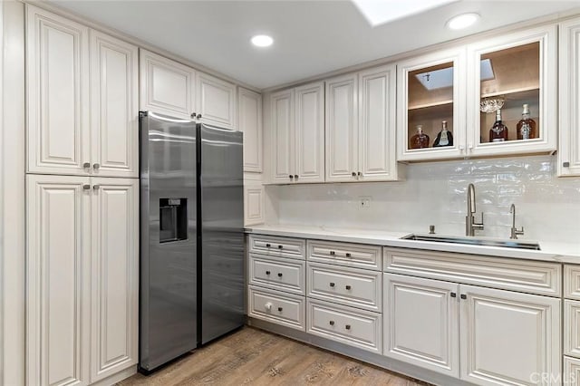 kitchen featuring stainless steel fridge, tasteful backsplash, sink, hardwood / wood-style flooring, and white cabinets